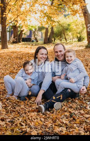 Familienportrait im Herbstpark. Kinder und Eltern posieren, lächeln, spielen und Spaß haben. Stockfoto