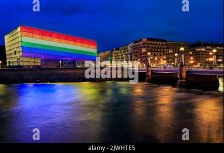 Die Skyline von San Sebastian mit dem Kursaal Congress Center und dem Auditorium Conference Center in Spanien, das bei Sonnenuntergang mit einer LGBT Pride-Regenbogenflagge geschmückt ist Stockfoto