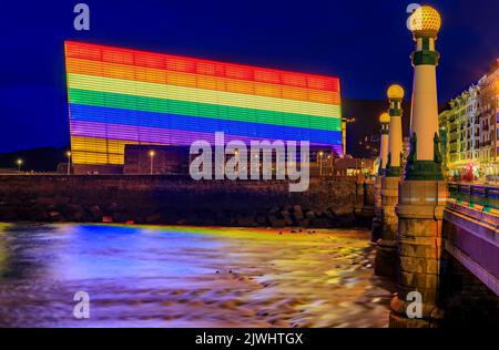 Die Skyline von San Sebastian mit dem Kursaal Congress Center und dem Auditorium Conference Center in Spanien, das bei Sonnenuntergang mit einer LGBT Pride-Regenbogenflagge geschmückt ist Stockfoto