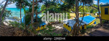 Blick auf den Ozean über gelbe Bungalows in einer familiengeführten Gastfamilie im Dorf auf Nanuya Lailai Island, Yasawa Islands, Fiji Stockfoto