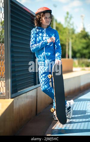 Nachdenklicher junger Skateboarder im Schutzhelm, der draußen steht Stockfoto