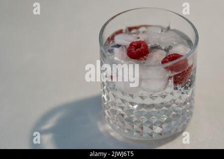 Gin und Tonic in doppeltem altmodischem Glas mit Eis und Himbeeren Stockfoto