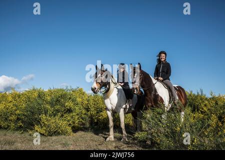 Portrait Mutter und Tochter reiten auf sonnigem, ländlichem Feld Stockfoto