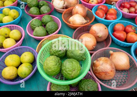 Bergamotten, Limetten, Zwiebeln und Tomaten in Körben am Marktstand Stockfoto