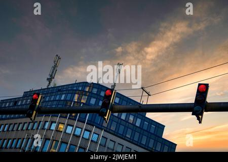 Eine Aufnahme von Ampeln mit niedrigem Winkel und rotem Licht auf horizontalem Mast im Hintergrund des Sonnenuntergangs Stockfoto