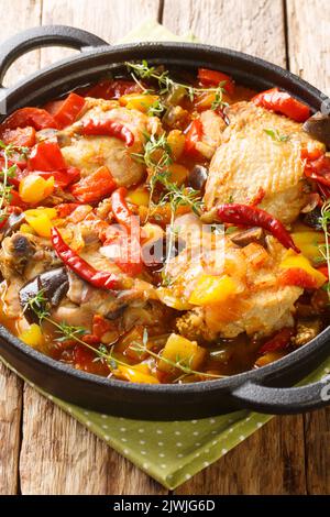 Kedjenou Chicken Ivory Coast Eintopf mit Gemüse in eigenem Saft in der Nähe in den Teller auf dem Tisch. Vertikal Stockfoto