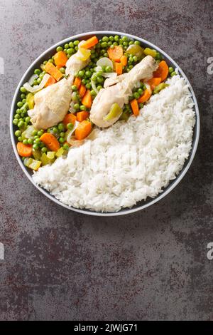 Pollo Arvejado oder Peas and Karotten Chicken Eintopf ist ein klassisches chilenisches Komfortgericht in Nahaufnahme auf dem Teller auf dem Tisch. Vertikale Draufsicht von oben Stockfoto