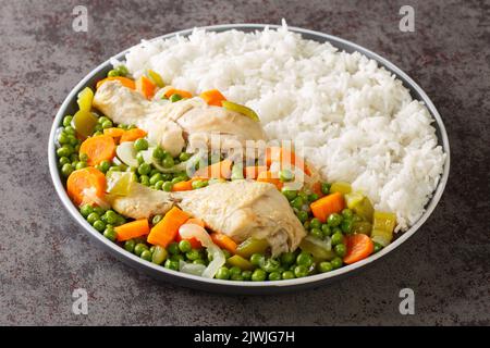 Chilenisches Essen Pollo Arvejado Hühnereintopf mit Karotten und grünen Erbsen, serviert mit Reis aus nächster Nähe auf einem Teller auf dem Tisch. Horizontal Stockfoto