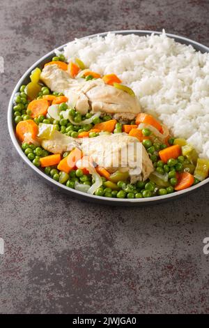 Pollo Arvejado oder Peas and Karotten Chicken Eintopf ist ein klassisches chilenisches Komfortgericht in Nahaufnahme auf dem Teller auf dem Tisch. Vertikal Stockfoto