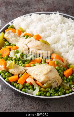 Erbsen und Karotten Hähncheneintopf Pollo Arvejado mit Reis garnieren, in der Nähe auf dem Teller auf dem Tisch. Vertikal Stockfoto
