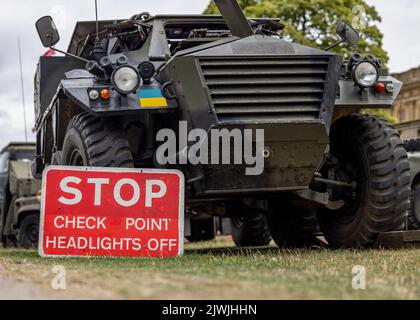 Ukrainischer Militärkontrollpunkt mit Panzerpanzerwagen an der Grenze der Ukraine. Stopp Kontrollpunkt rotes Schild Armee Ausrüstung. Stockfoto