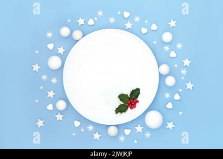 Weihnachtliche Essteller Tischdekor mit stacheligen roten Beeren und weiß mattierten Dekorationen. Abstraktes, minimalistisches Design für festliche Weihnachtsfeiertage Stockfoto