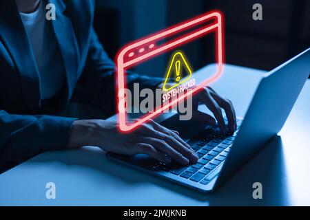 Junger Mann im Geschäftsanzug, der einen Laptop verwendet, der vor einer Warnung vor einem Cyberangriff und einer Schachtel mit Fehlermeldungen steht, weil er von den Hackern gehackt und kompromittiert wurde Stockfoto
