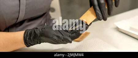 Maniküre-Meister nimmt Maniküre-Werkzeuge aus einem Kraftumschlag in einem Nagelstudio heraus Stockfoto