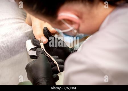 Professionelle Pediküre. Pediküre Master trägt Latexhandschuhe schneidet weibliche Fußnägel im Schönheitssalon, Nahaufnahme Stockfoto