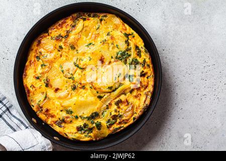 Traditionelle spanische Kartoffeltortilla oder Omelette in einer schwarzen Pfanne, Draufsicht. Stockfoto