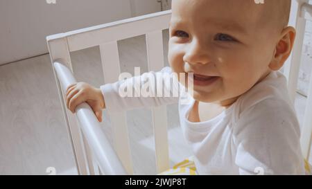 Nahaufnahme von fröhlichen Baby-Mädchen in weißen Kinderbett zu Hause stehen Stockfoto