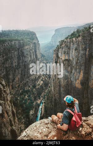Mann Reisender sitzt allein auf Klippe Wandern mit Rucksack Reise gesunden Lebensstil aktiven Urlaub Outdoor-Wanderer genießen Tazi Canyon Luftbild Stockfoto