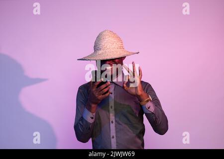 ein afrikanischer Mann, der sein Telefon hält, tut eine Geste in Ordnung Stockfoto