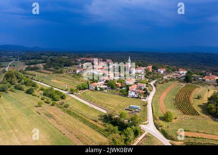Aus der Vogelperspektive auf ein wunderschönes Dorf Kostanjevica na Krasu, traditionelles Karstdorf in der Region Komen, an einem sonnigen Sommertag, kurz vor dem Sturm, Slowenien Stockfoto