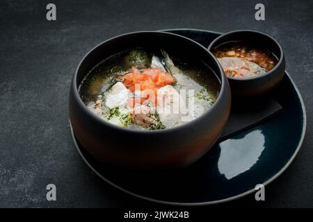 Lachsfischsuppe mit würziger Gemüsesauce, auf dunklem Hintergrund Stockfoto