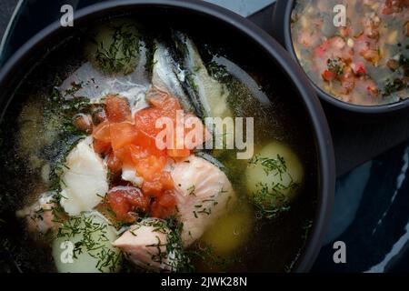 Lachsfischsuppe mit würziger Gemüsesauce, auf dunklem Hintergrund Stockfoto