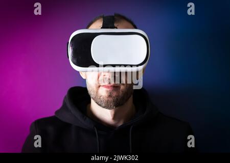 Der Mensch nutzt eine Virtual-Reality-Brille auf einem neon-Cyber-Hintergrund. Metaverse, futuristisches, Cyber-Spielkonzept. Hochwertige Fotos Stockfoto