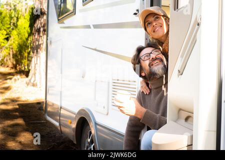 Ein glückliches und freies Paar junger reifer Menschen, die gemeinsam die Reise und den Sommerurlaub genießen, sitzen vor der Tür ihres Wohnmobil-Fahrzeugs. Tr Stockfoto