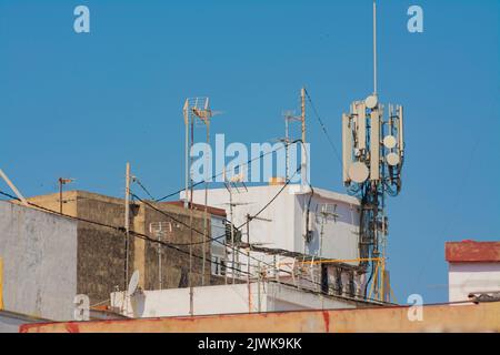 Turm mit WLAN-Netzwerk-Antennen, mit einigen Masten mit Fernsehantennen, auf dem Dach eines Wohnhauses Stockfoto