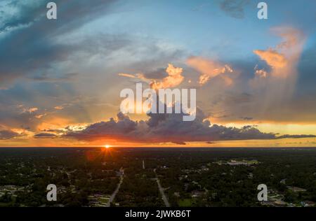 Luftlandschaftsansicht von privaten Vorstadthäusern zwischen grünen Palmen in Florida ruhige ländliche Gegend bei Sonnenuntergang Stockfoto