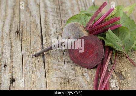 Rohe ganze und geschnittene Baby Rote Bete auf grauem rustikalem Holzhintergrund, freier Platz für Text Stockfoto