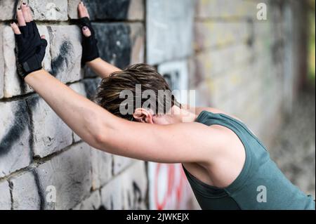 Porträt einer 36-jährigen weißen, müden Frau, die sich nach einem Work-out an einer Wand ausbreitet, Brüssel, Belgien Stockfoto