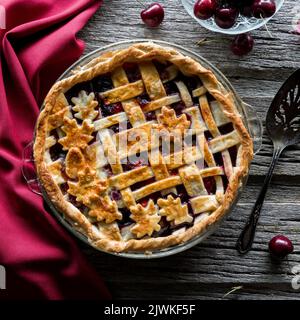 Ein Gitterkirschkuchen auf einem rustikalen Holzbrett, fertig zum Servieren. Stockfoto