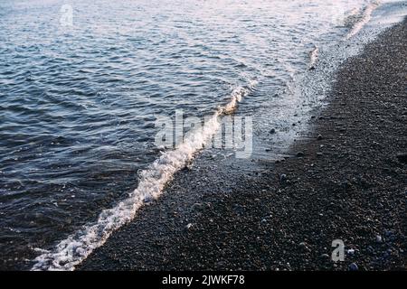 Meeresküste mit Kieselsteinen und Steinen am Abend bei Sonnenuntergang Stockfoto