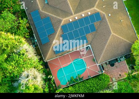 Luftaufnahme eines typischen amerikanischen Gebäudedachs mit Reihen blauer Photovoltaik-Solarpaneele zur Erzeugung sauberer ökologischer elektrischer Energie. Erneuerbar Stockfoto