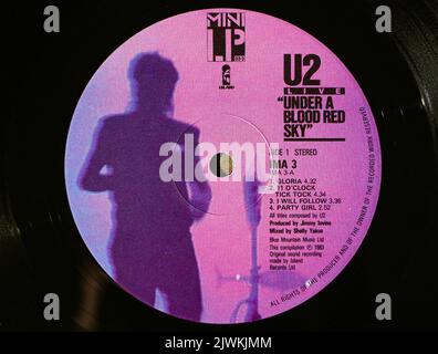 Foto-Nahaufnahme eines mittleren Labels auf einer original 1983 Pressung einer Vinyl-Disc unter einem Blut Red Sky U2 Live Stockfoto