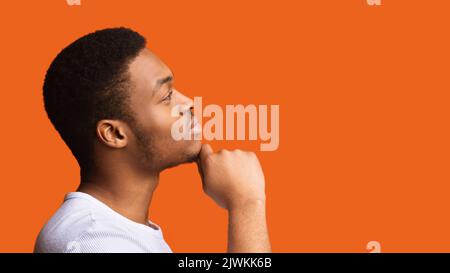 Profil Porträt Eines Nachdenklichen Schwarzen Mannes, Der Auf Orangefarbenem Hintergrund Denkt Stockfoto
