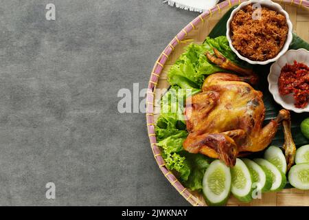 Ayam Ingkung Goreng oder Bakakak Hayam, tiefgebratenes Hähnchen, traditionelles indonesisches Rezept, in der Regel mit Sambal und Gemüse serviert. Draufsicht mit Stockfoto