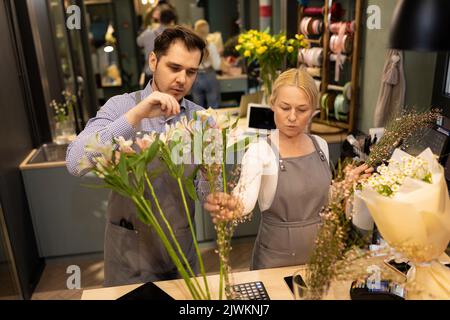 Ein Florist und sein Assistent kümmern sich in einem Blumengeschäft um frische Blumen Stockfoto