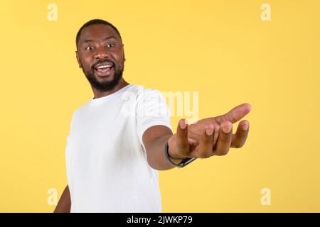 Aufgeregt Afrikanischer Amerikanischer Mann Hält Unsichtbares Objekt Auf Gelbem Hintergrund Stockfoto