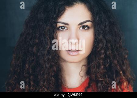 Junge Frau lockiges Haar fixiert Blick Konzentration Stockfoto