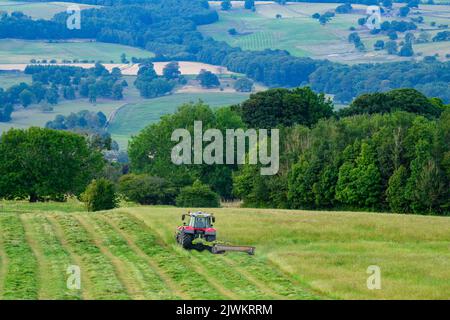 Red Massey Ferguson 7719 S Traktor & Claas Disco 3200c Strohhalm - Hänge-Weideland, malerische Wharfedale Countryside, Yorkshire, England Großbritannien. Stockfoto