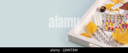 Pharmazeutisches Banner mit Pillen in Blisterpackung mit Herbstblättern auf einem Holztablett auf blauem Hintergrund mit Kopierplatz. Konzept der Einnahme von Pille und ich Stockfoto