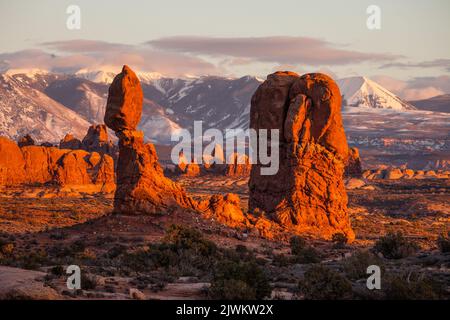 Balanced Rock im Arches National Park in der Nähe von Moab, Utah. Im Hintergrund befinden sich der Turret Arch und die La Sal Mountains. Stockfoto