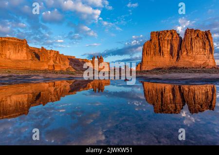 Die drei Klatsch, Sheep Rock und The Organ, spiegelten sich in einem ephemeren Regenwasserpool im Arches National Park, Moab, Utah, wider. Abschnitt „Courthouse Towers“. Stockfoto