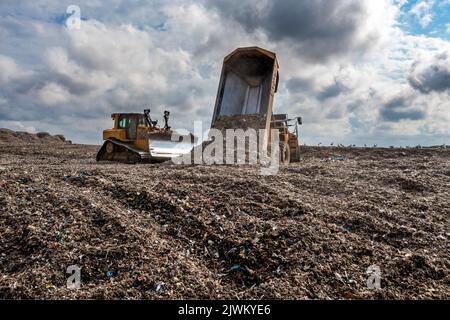 Ein Müllwagen auf einer großen Mülldeponie, der Müll in ein Umweltbild einschleuste Stockfoto