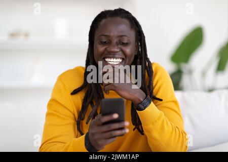 Online-Kommunikation. Porträt Eines Fröhlichen Afroamerikanischen Guy Mit Smartphone Zu Hause Stockfoto