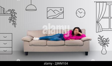 Schöne glückliche junge schwarze Frau, die auf dem Sofa liegt und lächelt Stockfoto