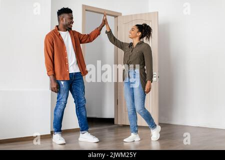 Fröhliches Schwarzes Paar, Das Hohe Fünf Im Neuen Haus Stehend Gibt Stockfoto
