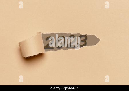 Die Zahl 2023 erscheint durch einen Riss in einem roten Karton ...